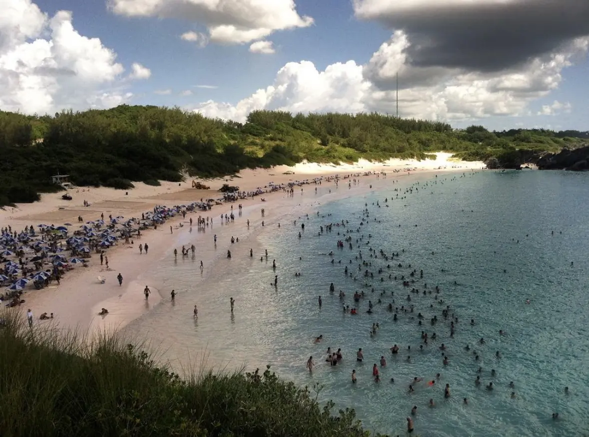 Beach cove with swimmers and umbrellas beneath dramatic clouds