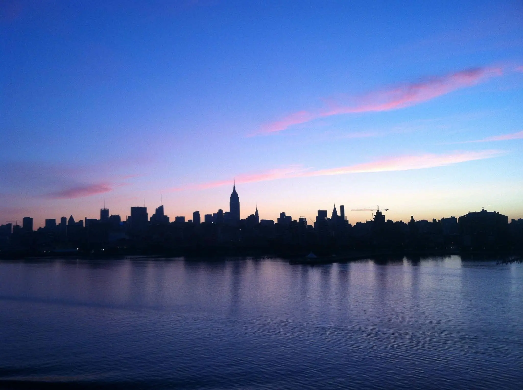 City skyline at dusk with pink clouds over the water