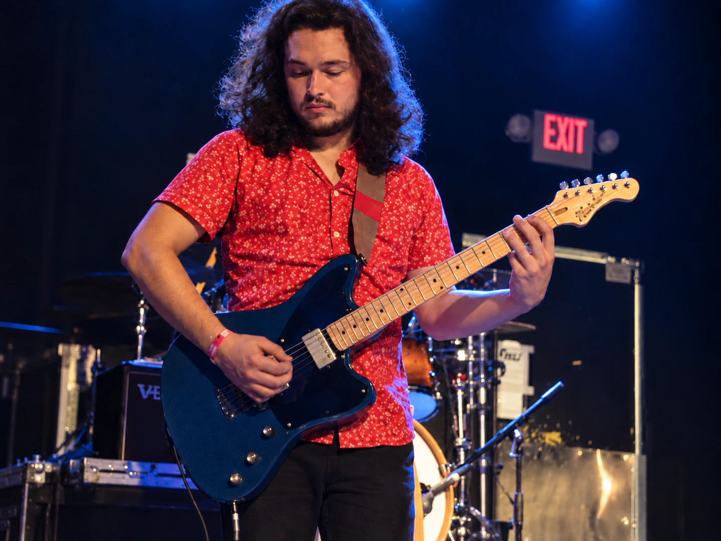 Guitarist playing a blue electric guitar under blue and warm stage lights