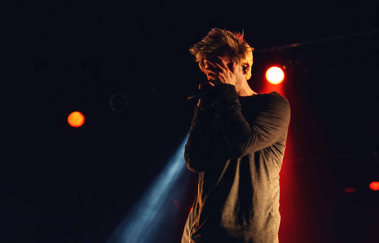 Singer on a dark stage under warm orange lights